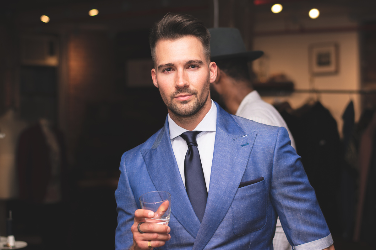 Man in Blue Suit Holding Glass in Right Hand