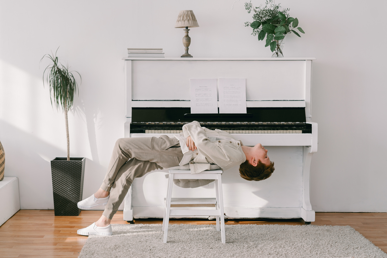 A Boy Lying Down on a Piano Chair