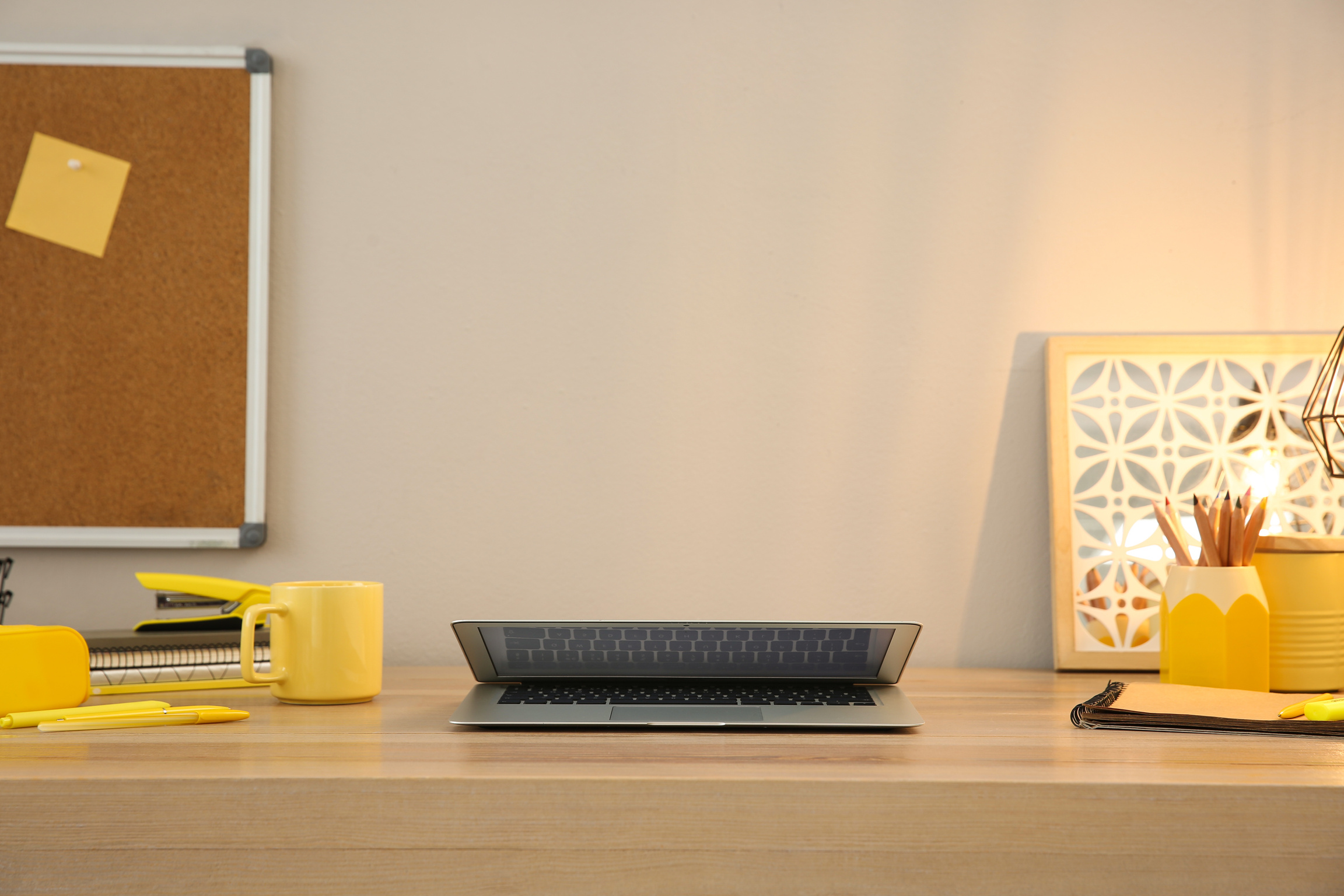 Stylish workplace with laptop on wooden desk near light wall. Interior design