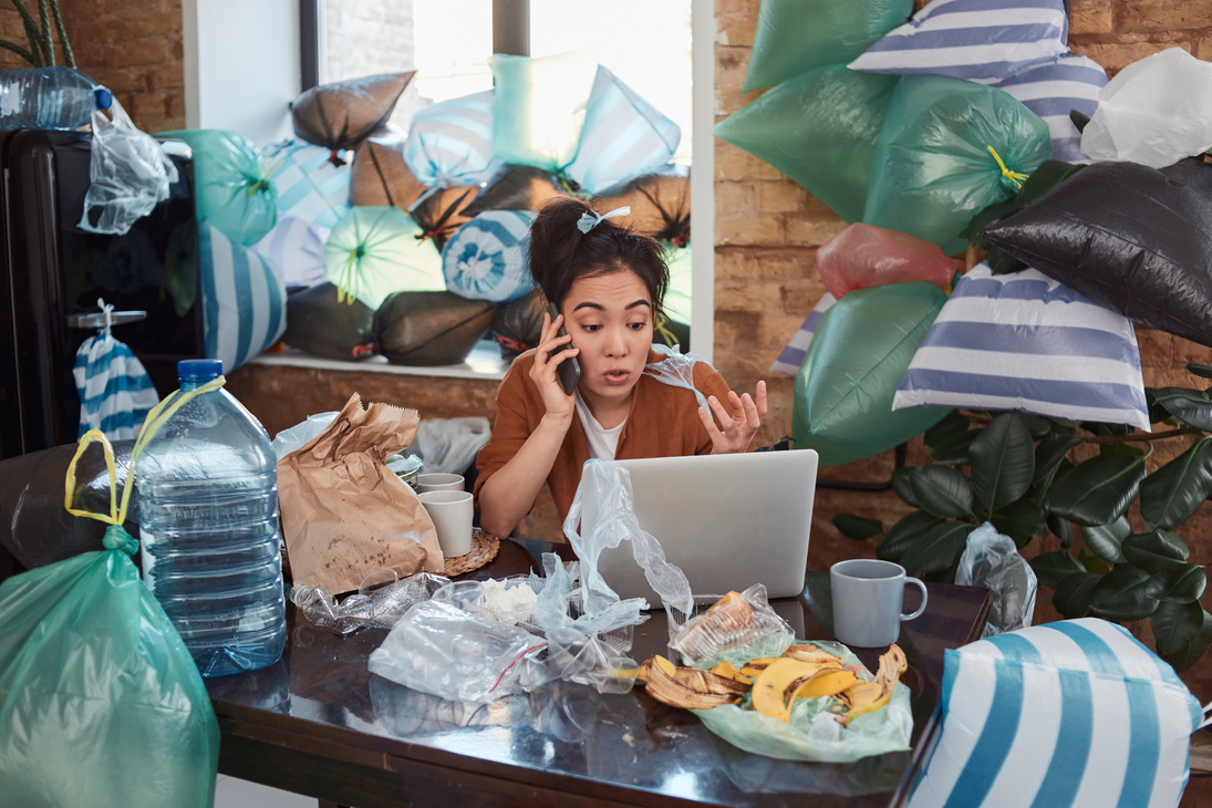 Female speaking on phone in a messy room