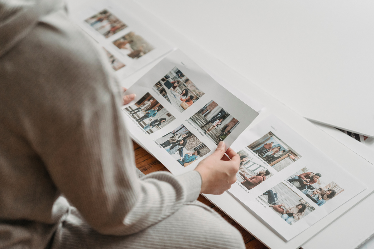 Crop unrecognizable woman looking through printed photos in album